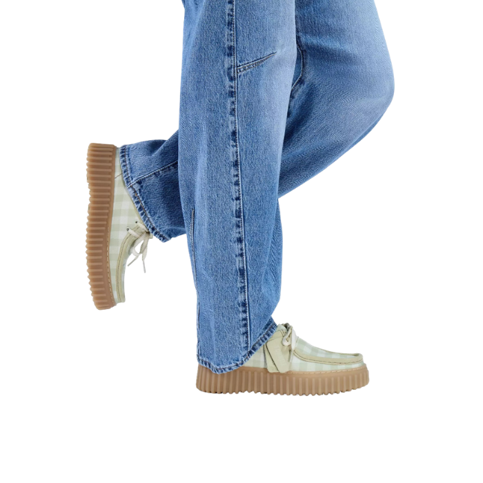 Model wearing sage and white checkered platform sneakers and blue jeans.