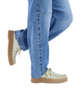 Model wearing sage and white checkered platform sneakers and blue jeans.