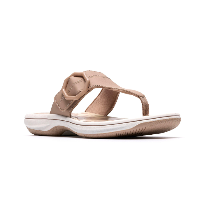 Beige thong sandal with a tan octagonal buckle, floral beige footbed, white midsole and beige outsole.