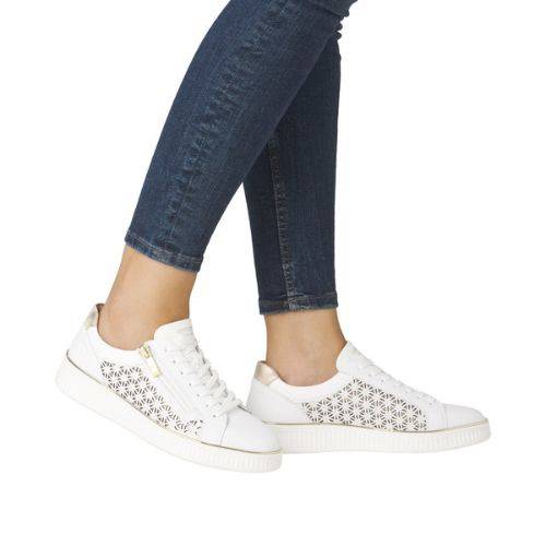 Model wearing white Remonte D2E03 lace-up sneakers with jeans, highlighting stylish laser-cut leather and gold heel detail.