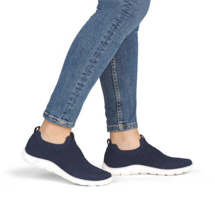Navy slip-on sneakers worn with blue jeans.
