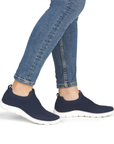 Navy slip-on sneakers worn with blue jeans.