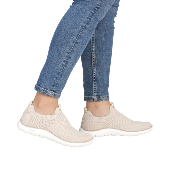 Beige slip-on sneakers worn with blue jeans.