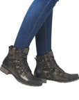 Bronze ankle boots with light accents worn with blue jeans.