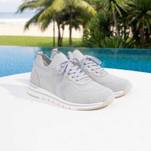 Light grey Women&#39;s Remonte R6712 Slip-On Sneakers placed by a poolside, emphasizing breathable textile and sporty design.