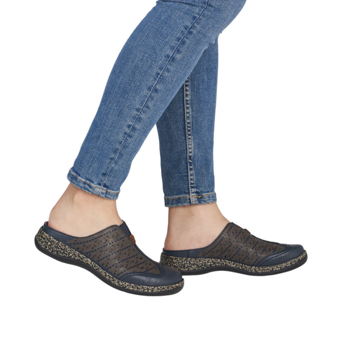 Person wearing dark casual perforated clogs and blue jeans.