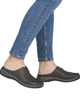 Person wearing dark casual perforated clogs and blue jeans.