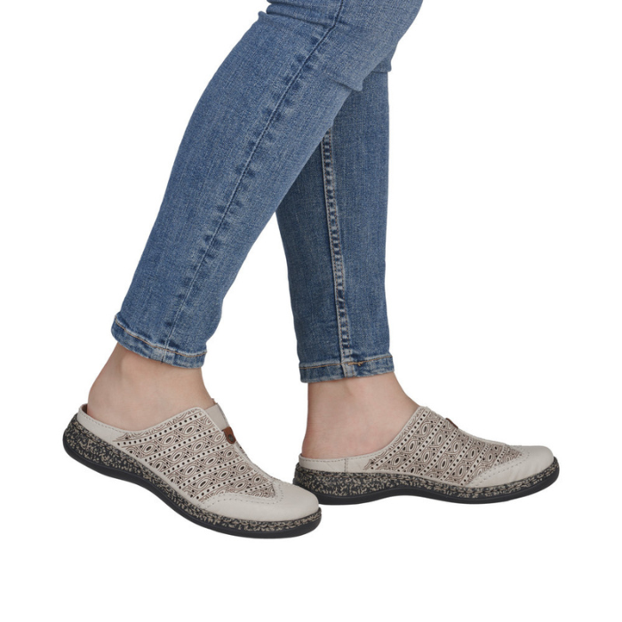 Person wearing Beige slip-on clogs with blue jeans.