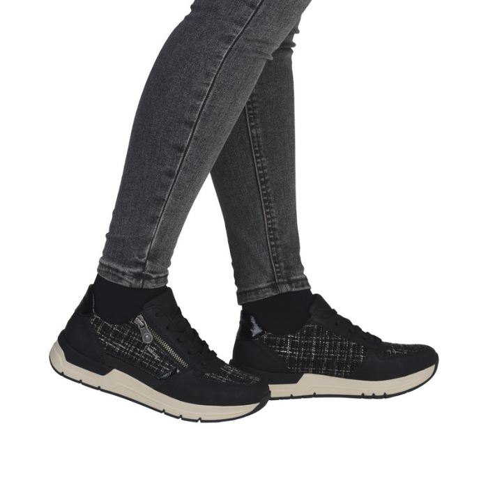 Black sneakers with plaid accents worn with gray jeans.