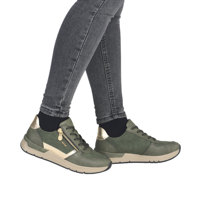 Green sneakers  with gold accents worn with gray jeans.