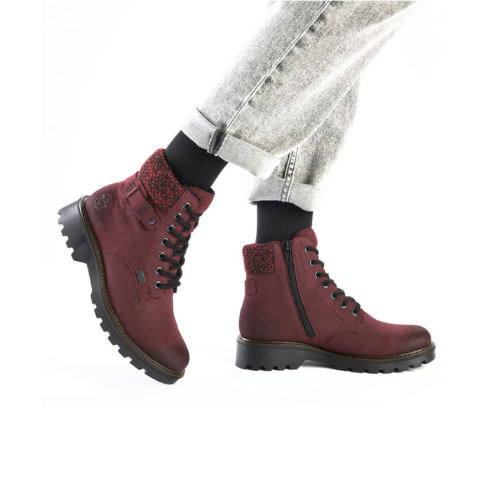 Red combat boots with black soles worn with light grey jeans.