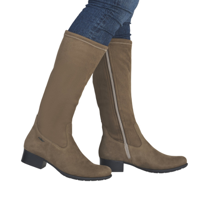 Woman wearing tall taupe boots and blue jeans.