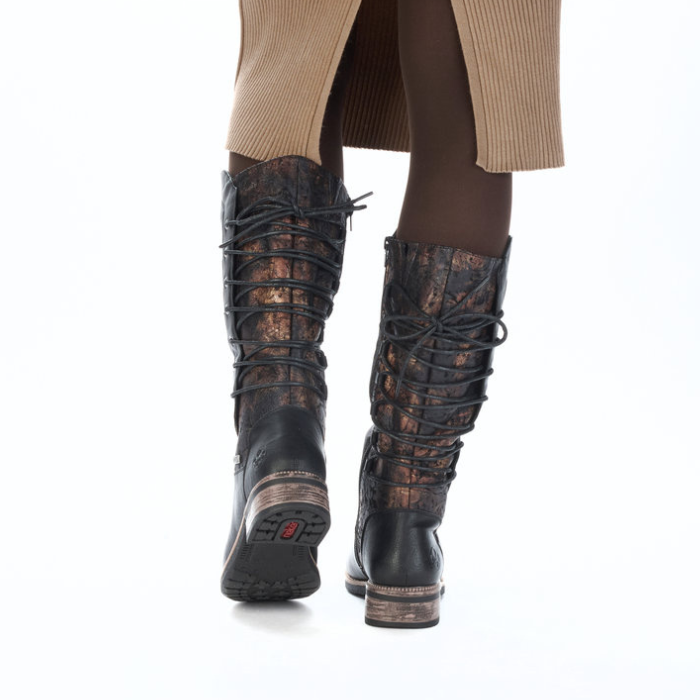 Black knee-high boots with lace-up design worn by a person in brown leggings and tan ribbed dress.