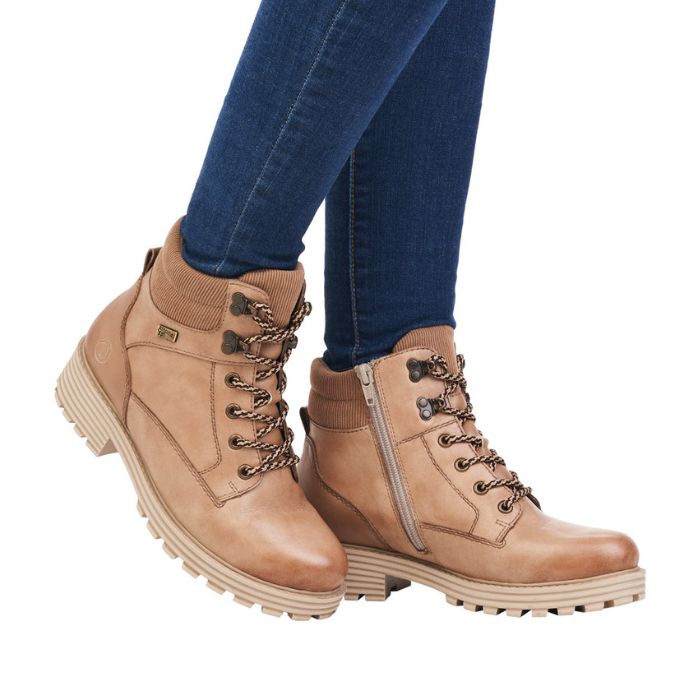 Legs in jeans wearing tan brown lace up boot.