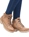 Legs in jeans wearing tan brown lace up boot.