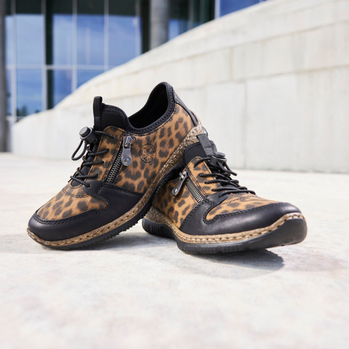 Pair of leopard print sneakers on a light surface with a blurred street background