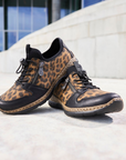 Pair of leopard print sneakers on a light surface with a blurred street background