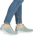 Light green slip-on sneakers worn with blue jeans.