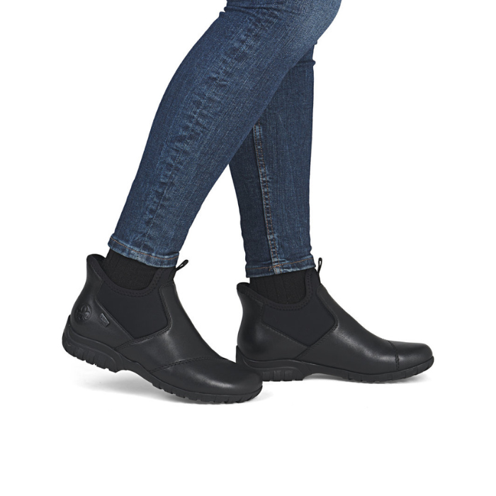 Black ankle boots worn with blue jeans.
