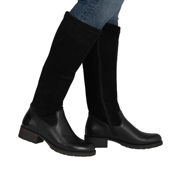 Woman wearing black tall boots with low block heel and blue jeans.