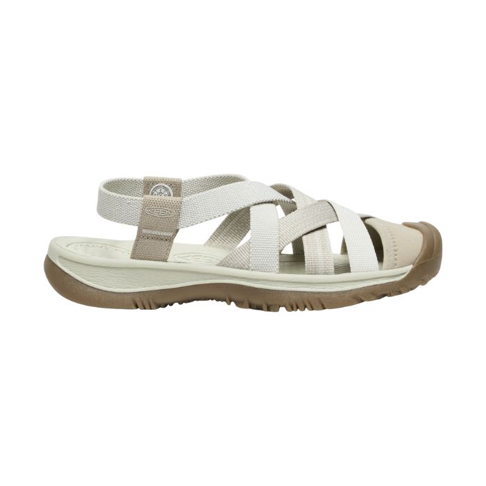 Walking sandal with criss crossing straps in various shades of white and rugged brown outsole.