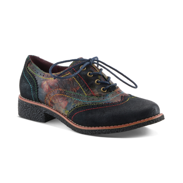 An Oxford shoe with dark navy toe cap and heel, a painterly floral patterned leather upper in red, orange, green, and blue tones, blue waxed laces and rainbow stitching accents.