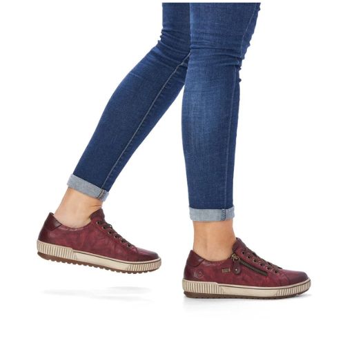 Woman wearing blue jeans and red leather  lace up sneakers with side zippers