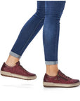 Woman wearing blue jeans and red leather  lace up sneakers with side zippers