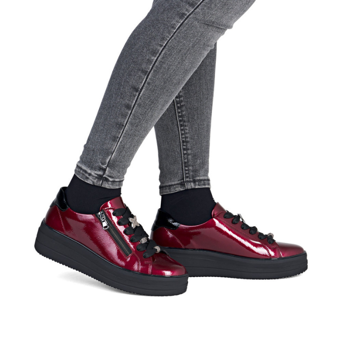 Patent Burgundy platform sneakers worn with gray jeans.