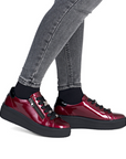 Patent Burgundy platform sneakers worn with gray jeans.
