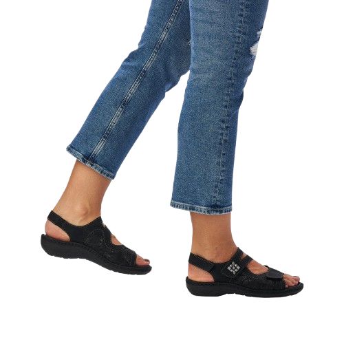 Girl in jeans wearing black backstrap sandals with silver accents.