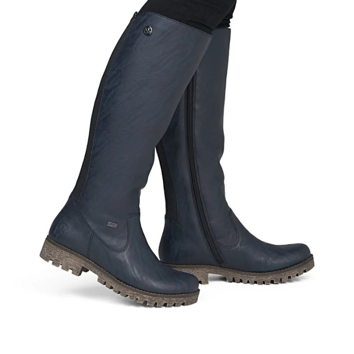 Dark navy blue knee-high riding boots with side zippers and rugged brown lugged outsole.