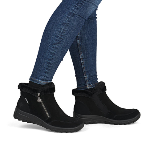 Black ankle boots with faux fur trim and a side zipper, shown on a model wearing blue jeans.