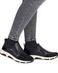 Black slip-on shoes worn with gray jeans.