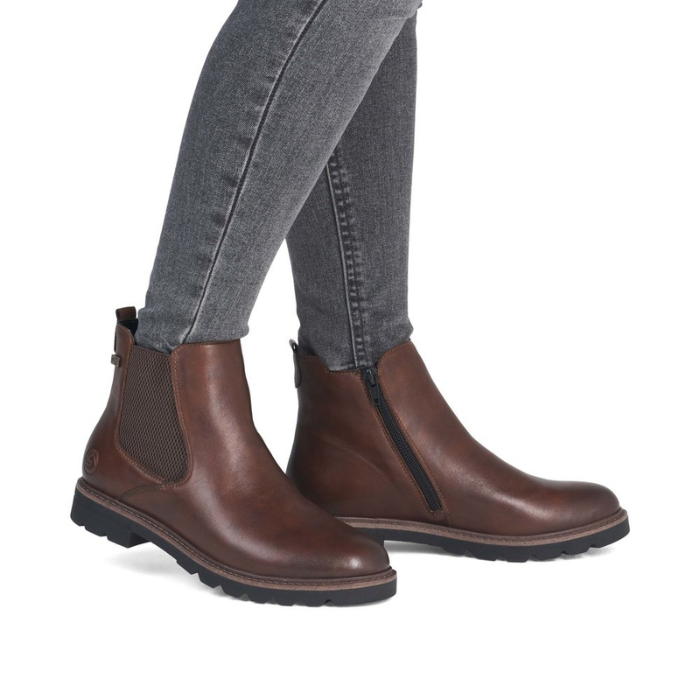 Brown leather chelsea boots worn with gray jeans.
