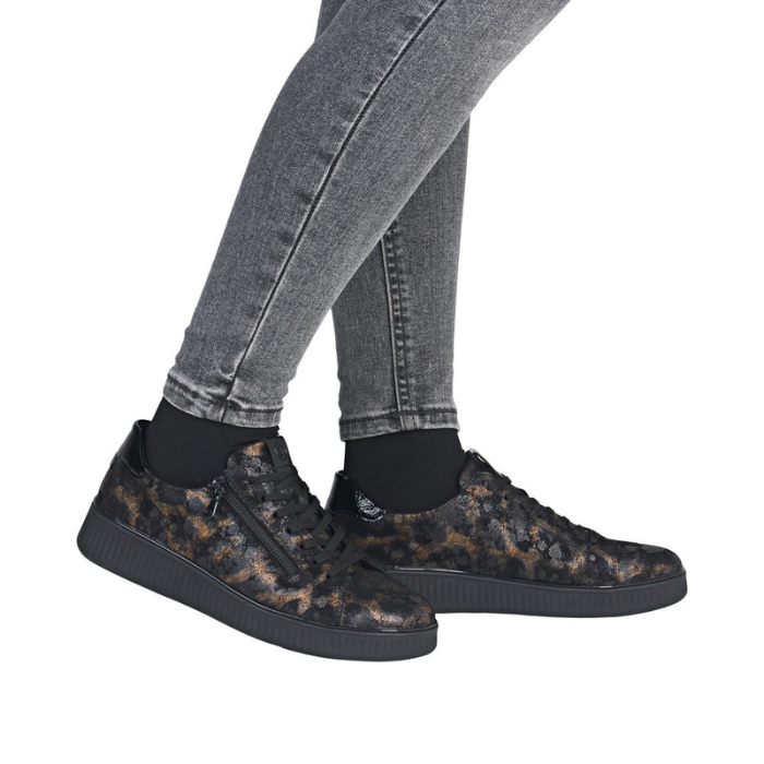 Black leopard patterned sneakers worn with gray jeans.