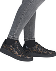 Black leopard patterned sneakers worn with gray jeans.