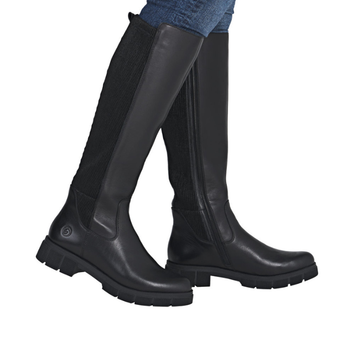 Black knee high boots worn with blue jeans.