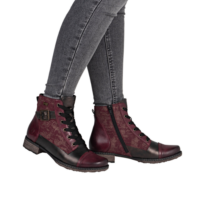 Woman in green jeans wearing red and bronze ankle boots with low heel.