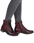 Woman in green jeans wearing red and bronze ankle boots with low heel.