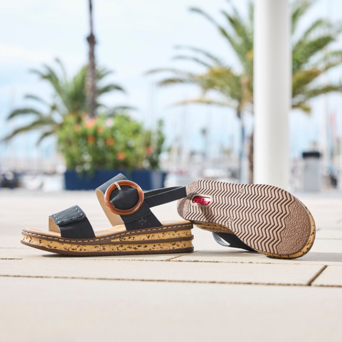 Pair of sandals on a cement pathway with a blurred outdoor background.