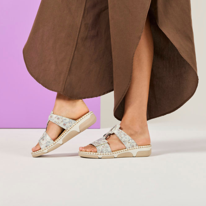 Person wearing floral slide sandals with a brown skirt.