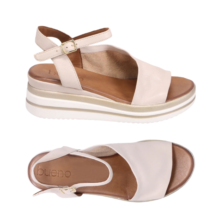 Pair of beige sandals with slingback and open toe d'Orsay style upper with gold buckle, white and gold lined wedge midsole and tan Bueno logo'd footbed.s
