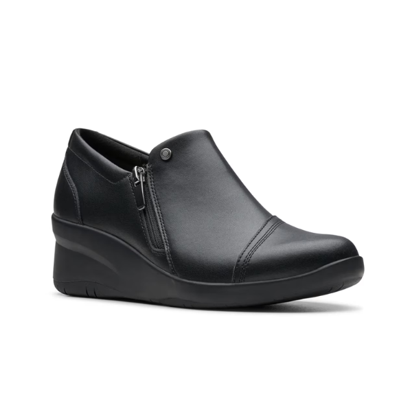 Black leather wedge ankle slip-on shoe. Has a detailed silver button above side zipper. Small detailed diagonal stitching on toe.