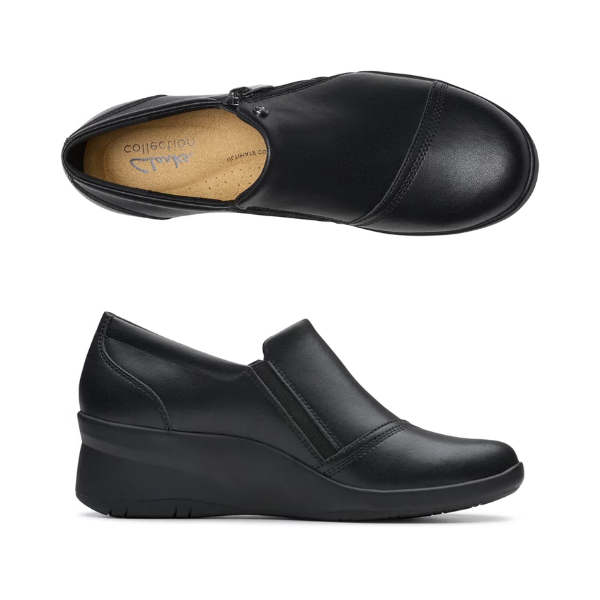 Top and Profile of Black leather wedge ankle slip-on shoe. Has a detailed silver button above side zipper. Small detailed diagonal stitching on toe. Padded tan footbed has the black Clarks logo at heel.