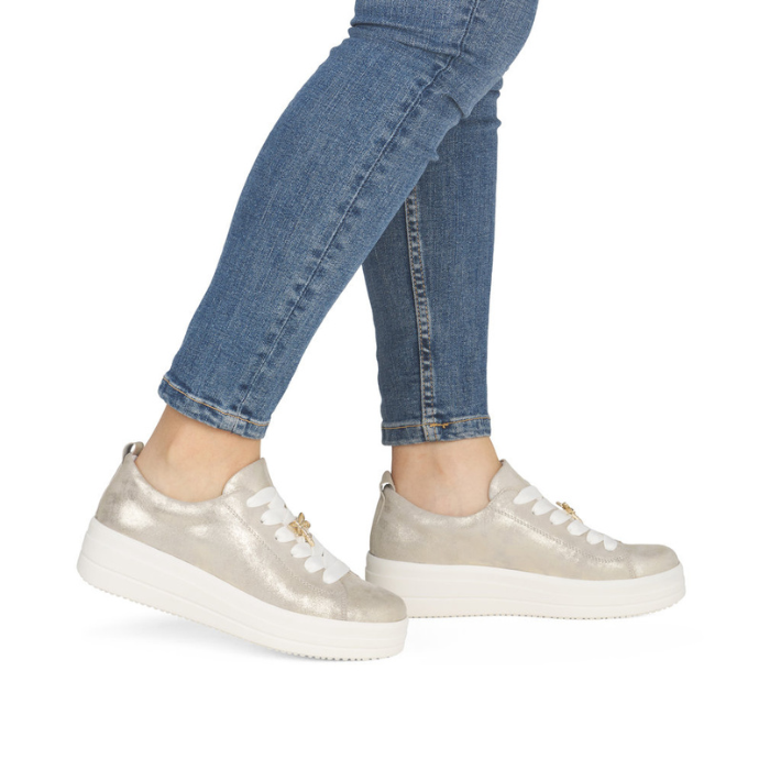 Gold platform sneakers worn with blue jeans.
