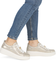 Gold platform sneakers worn with blue jeans.