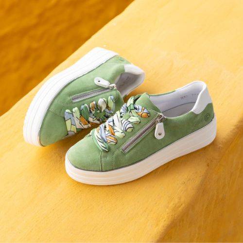 Green Remonte D1C06 women's platform sneakers with colorful laces and zipper, styled on a yellow background for a vibrant look.