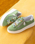 Green platform sneakers with colorful laces and zipper, styled on a yellow wall ledge.