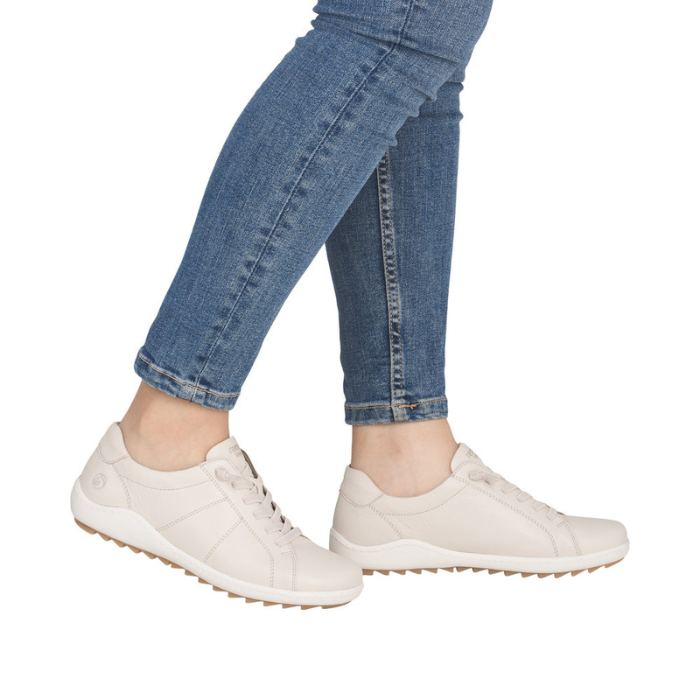 Beige sneakers worn with blue jeans.